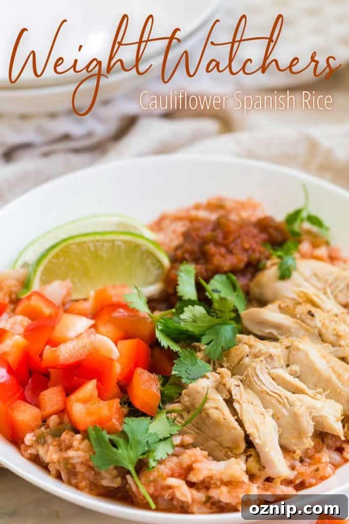 WW Cauliflower Spanish Rice on a white plate with chicken, cilantro and a lime wedge