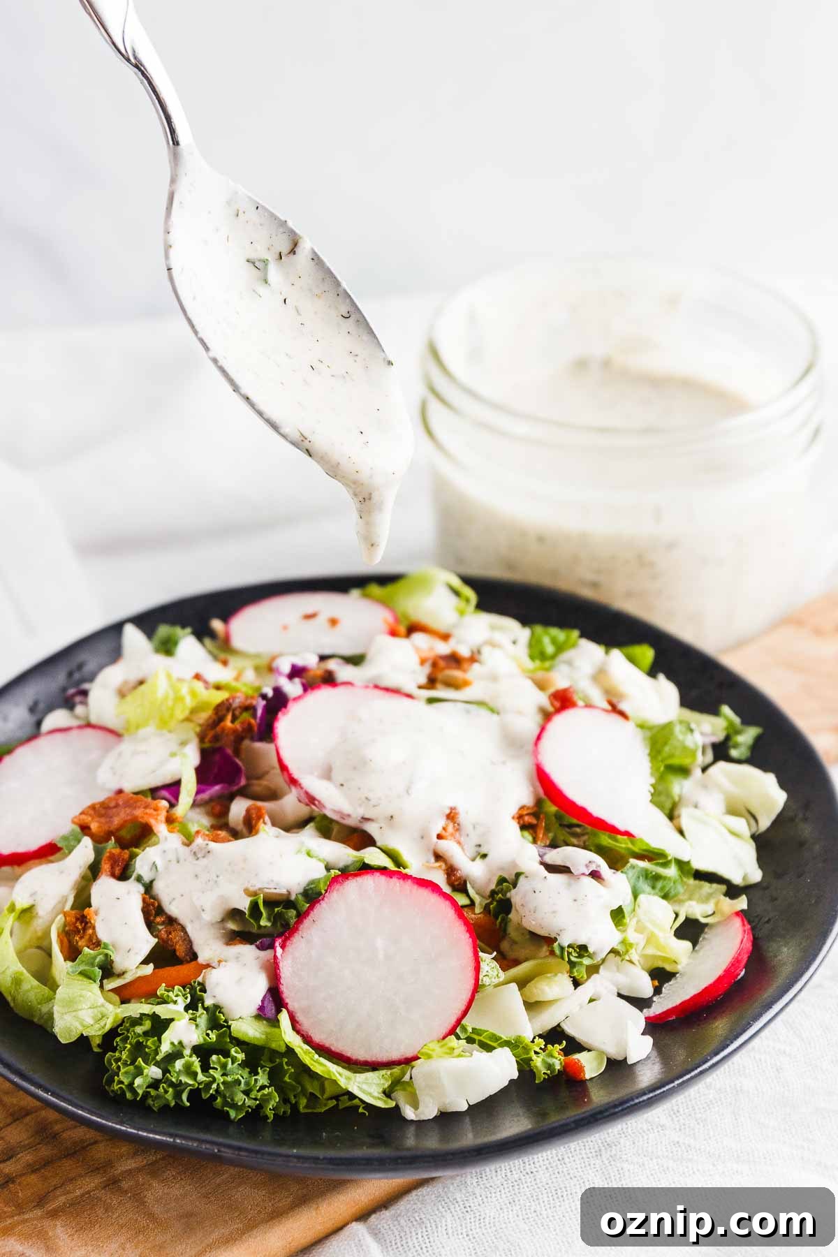 Pouring keto ranch dressing over a salad.