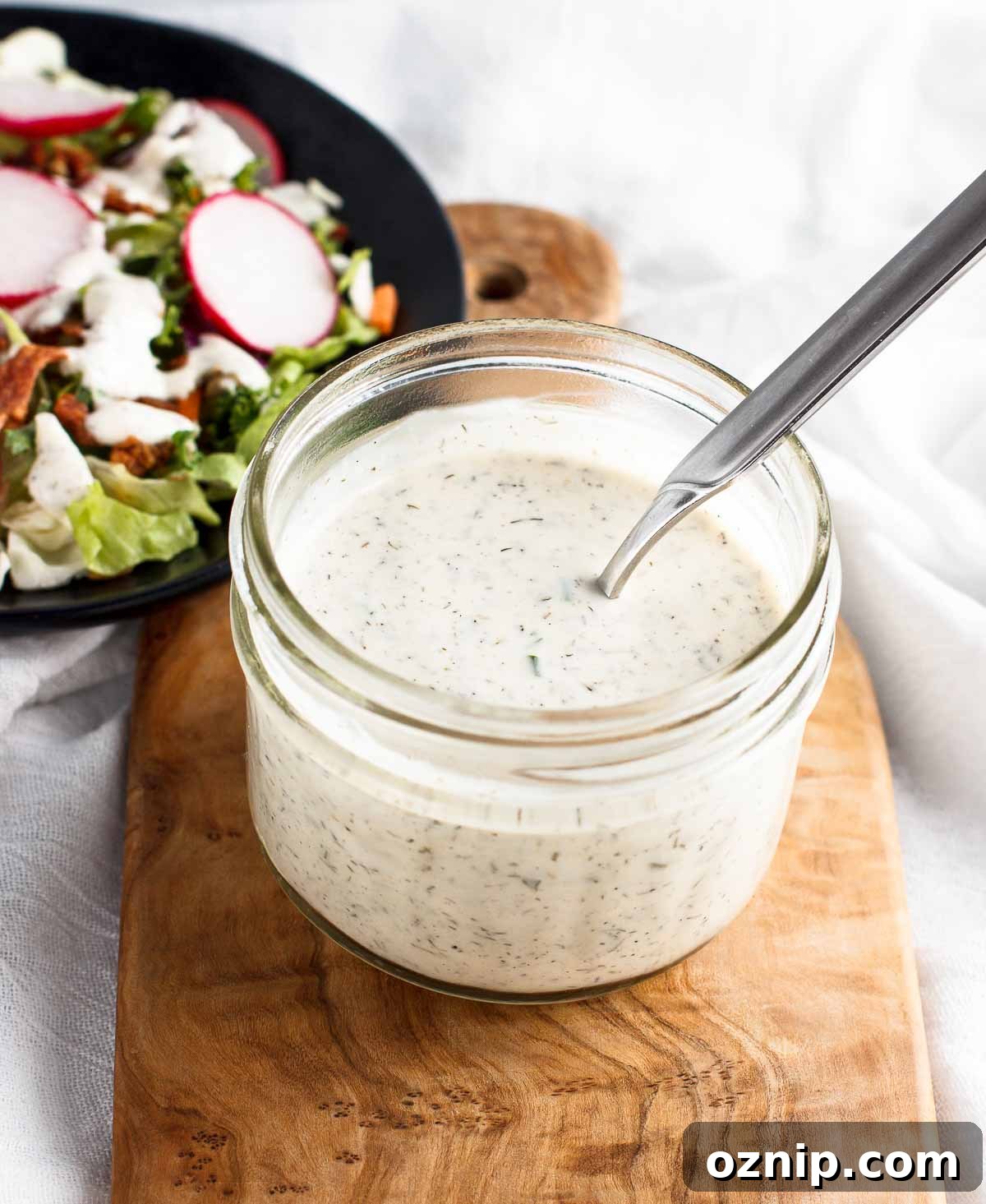 Stirring homemad keto ranch dressing in a mason jar.