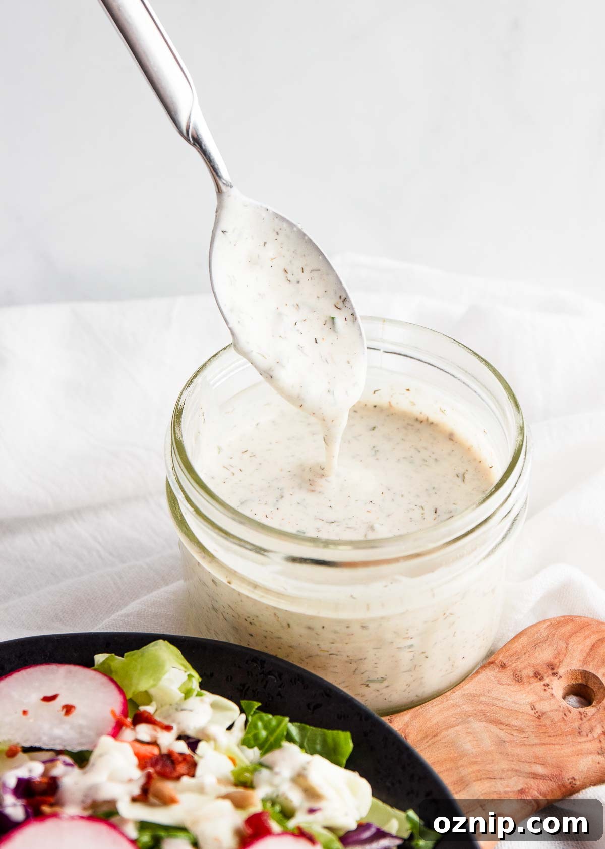 Stirring homemad keto ranch dressing in a mason jar.