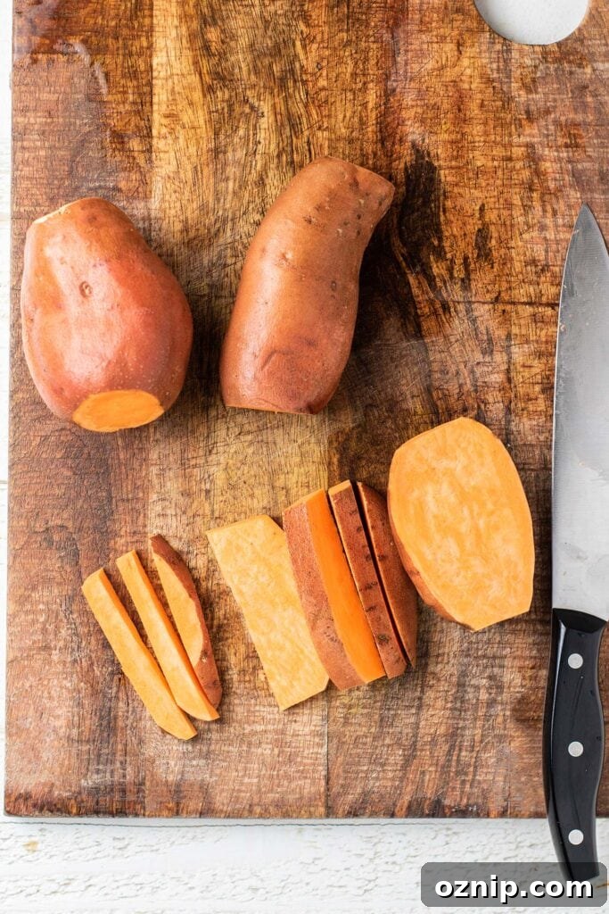 Sweet potatoes on a cutting board showing the process of cutting evenly shaped sweet potato fries.