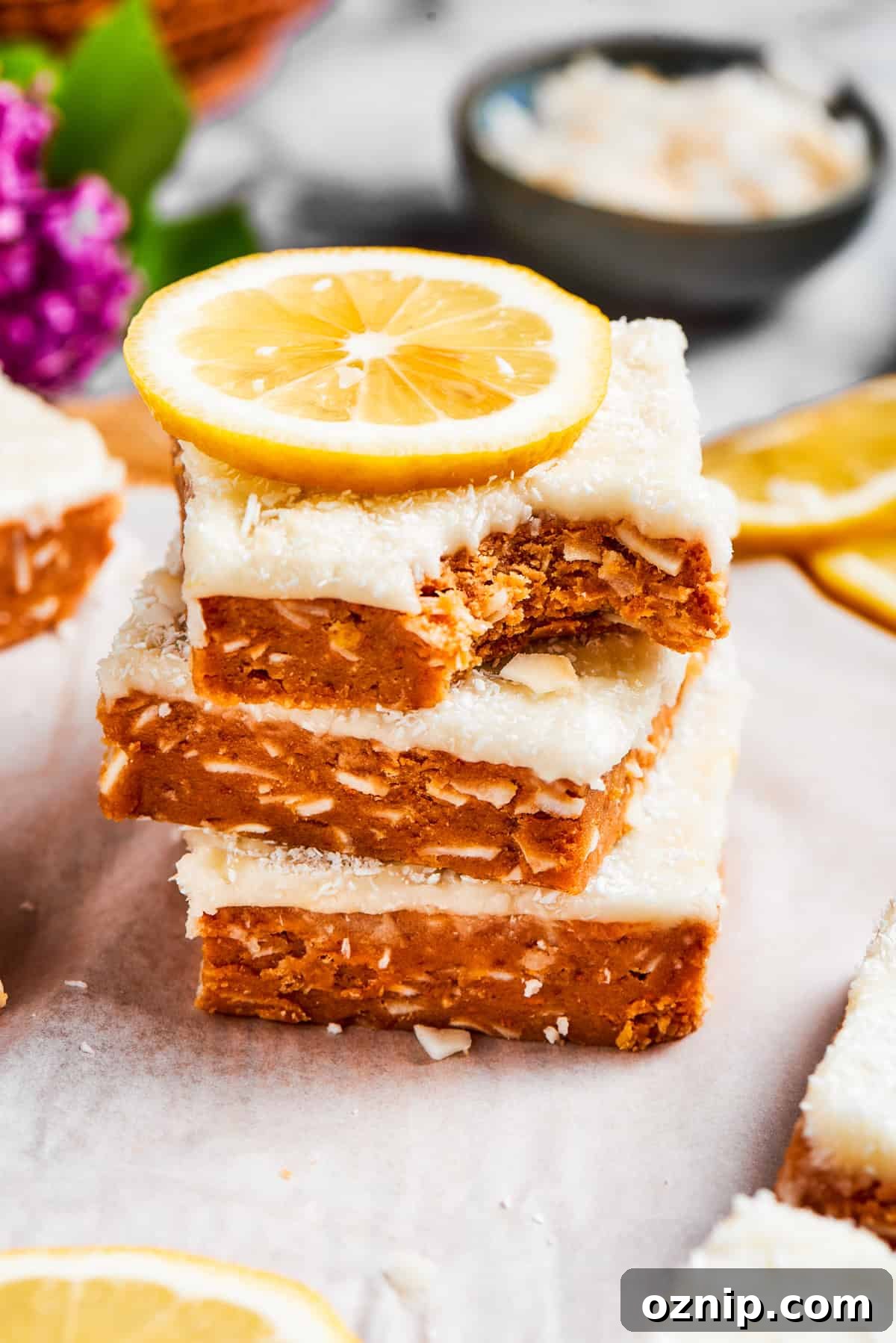 Three lemon slice squares, stacked, with the top one missing a bite.