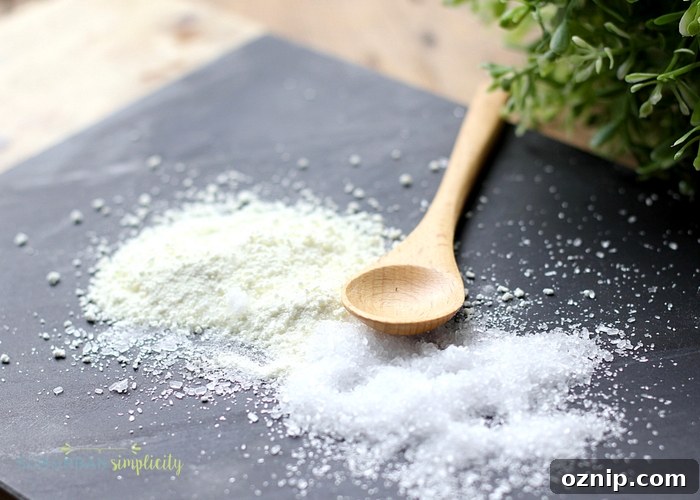 DIY Peppermint Foot Soak for Tired Feet 5 The ingredients for peppermint foot soak, salt and powdered milk, spread on a piece of gray slate. There is a wooden spoon laying next to the ingredients.