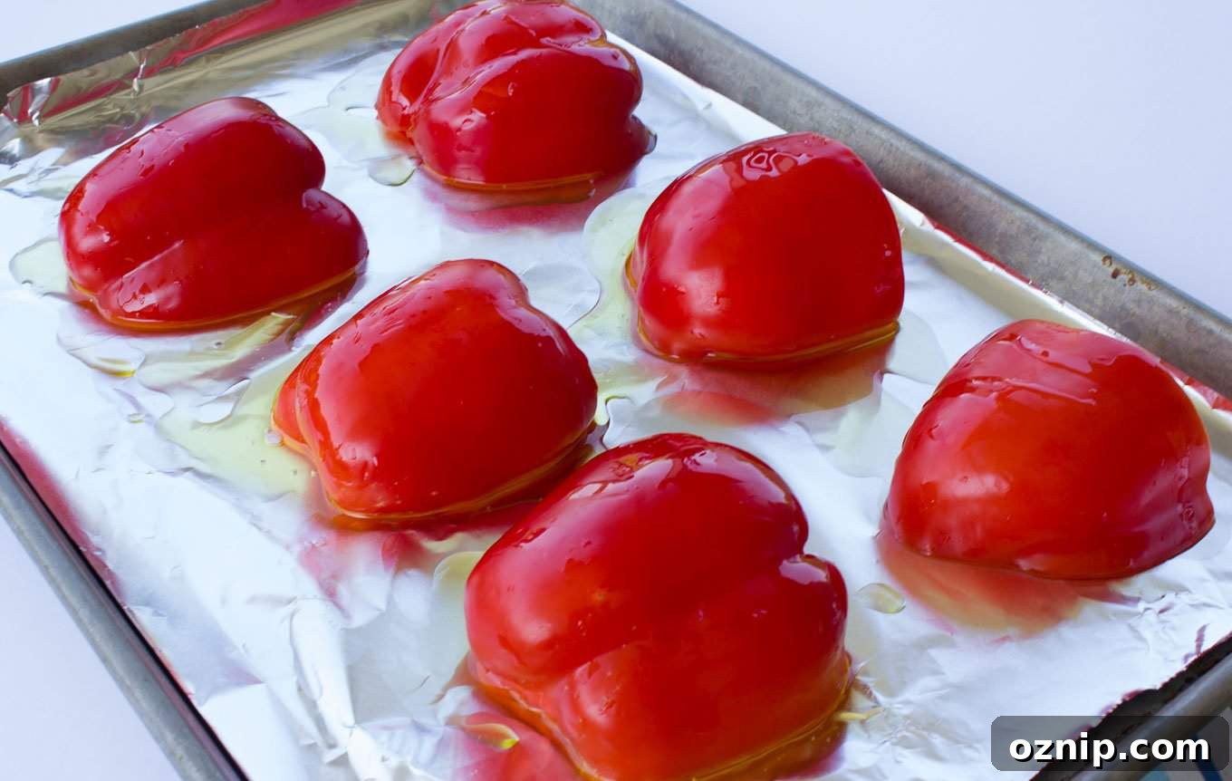 How to Roast Red Peppers: Oven, Grill and Stovetop Methods 3 six raw red pepper halves cut side down on a cookie sheet with olive oil