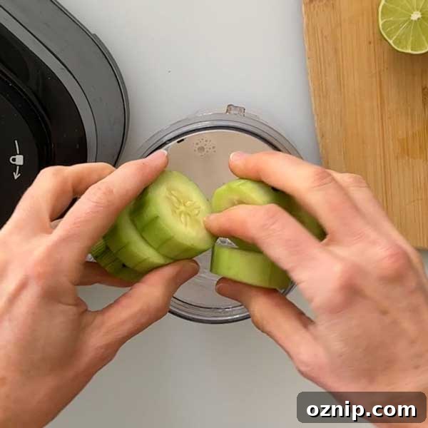 Adding sliced cucumbers to the smoothie cup.