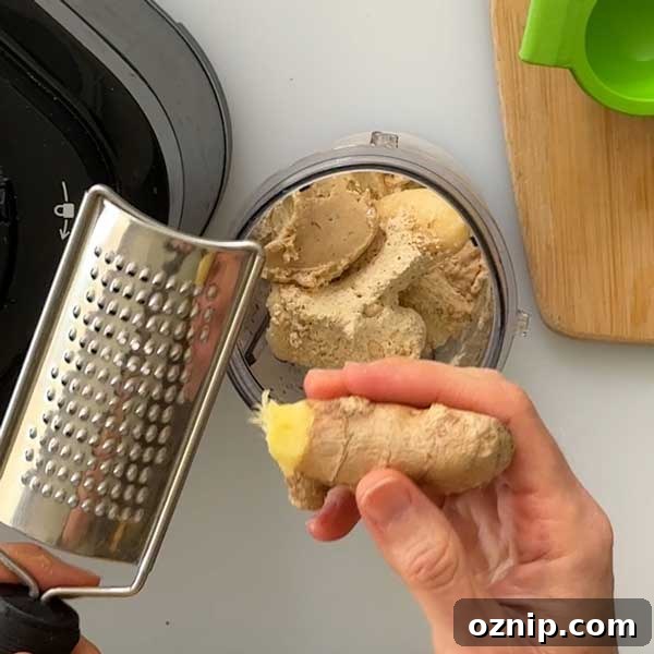Grating fresh ginger into the smoothie cup.