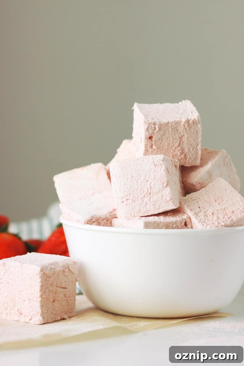 a bowl of homemade strawberry marshmallows with fresh strawberries