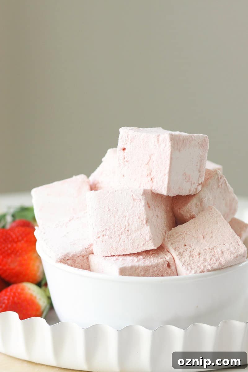 a bowl of homemade strawberry marshmallows with fresh strawberries