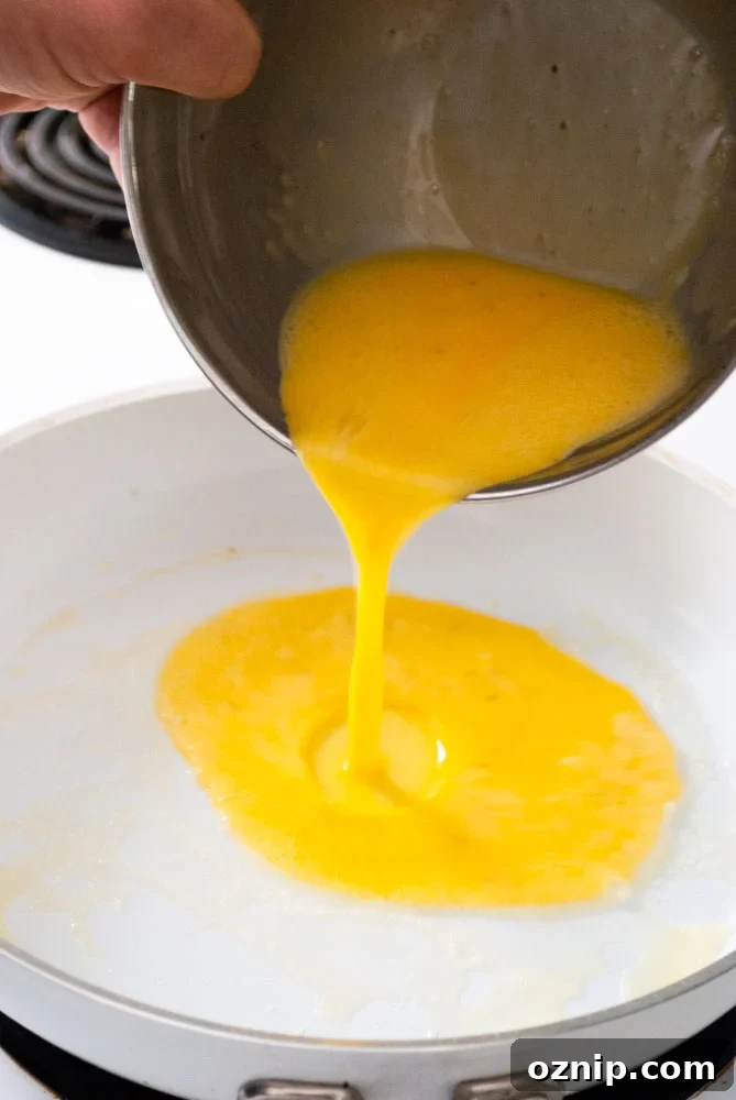 Mushroom Omelette Recipe with Cheese and Herbs 4 Beaten eggs cooking in a skillet for an omelette.