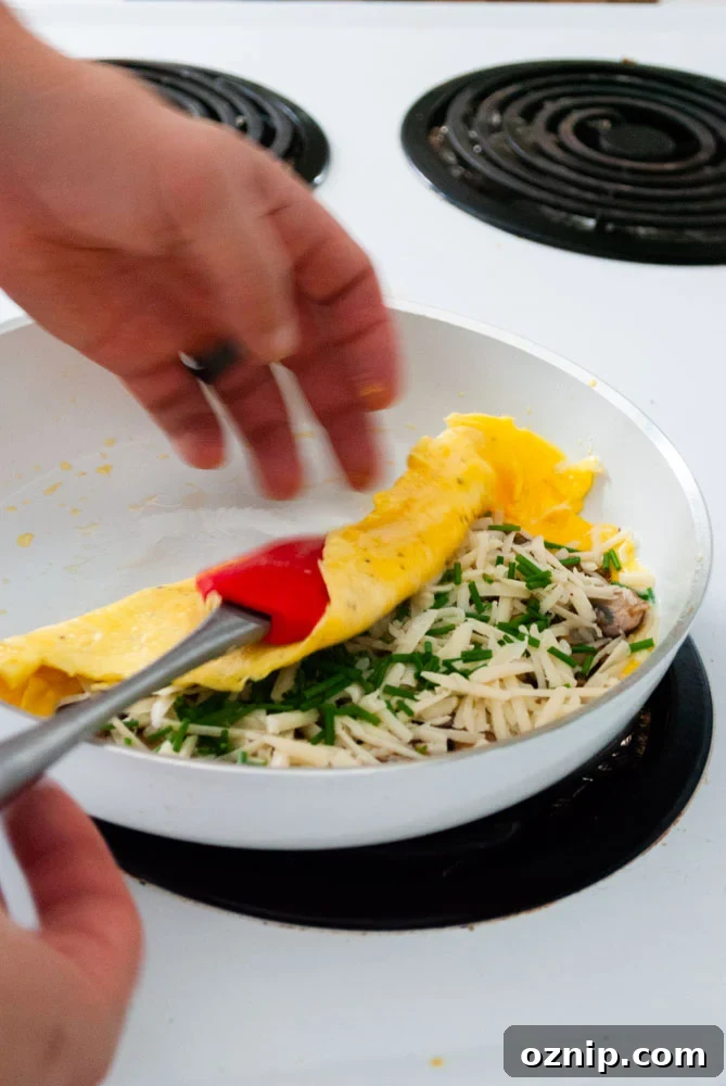 Mushroom Omelette Recipe with Cheese and Herbs 6 Folding a mushroom and Gruyere omelette in a skillet.