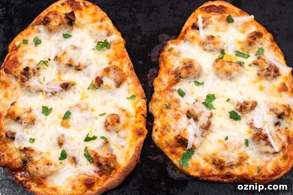 Baked chicken tikka pizza on baking sheet.