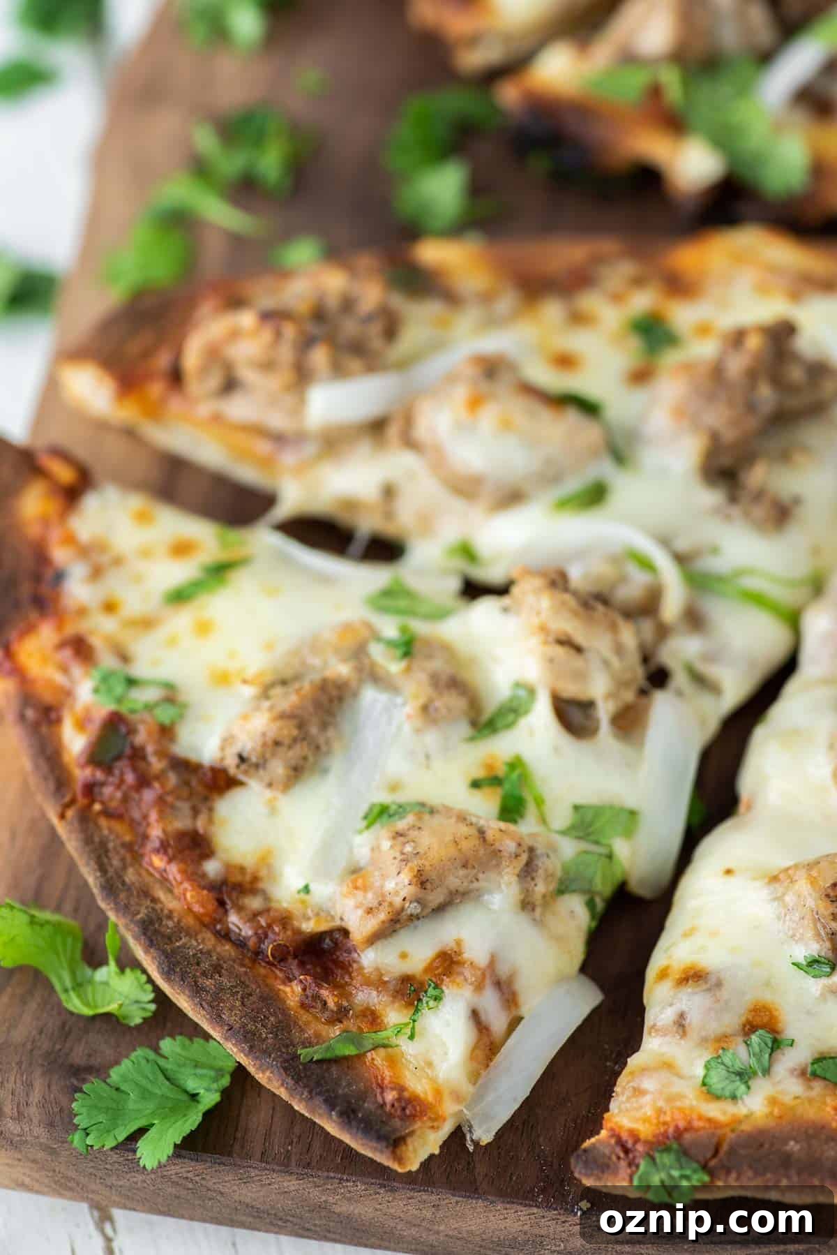 Slice of chicken tikka pizza being pulled away on wood board.