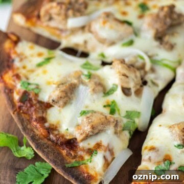Slice of chicken tikka pizza being pulled away on wood board.