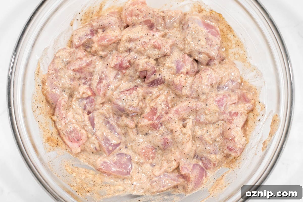 Chicken marinating in glass bowl.
