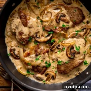 Pork steaks in a creamy mushroom sauce in a frying pan.