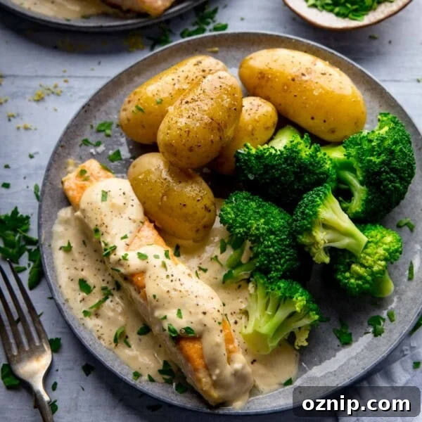 Salmon on a grey plate with creamy white wine sauce, broccoli and new potatoes