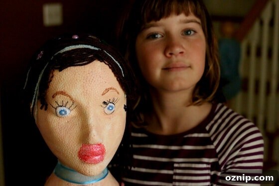 Styrofoam Head Self Portrait Art Project for Kids 4 girl holding styrofoam head painted to look like herself