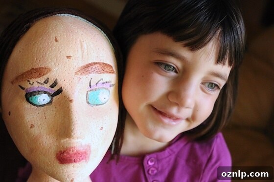 Styrofoam Head Self Portrait Art Project for Kids 10 Girl holding styrofoam mannequin head painted as self-portrait