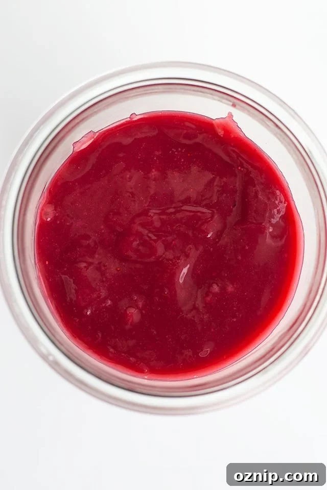 Mixed Berry Curd Recipe 4 A close-up, overhead view of a jar filled with bright red cranberry sauce, reminiscent of a vibrant berry curd.