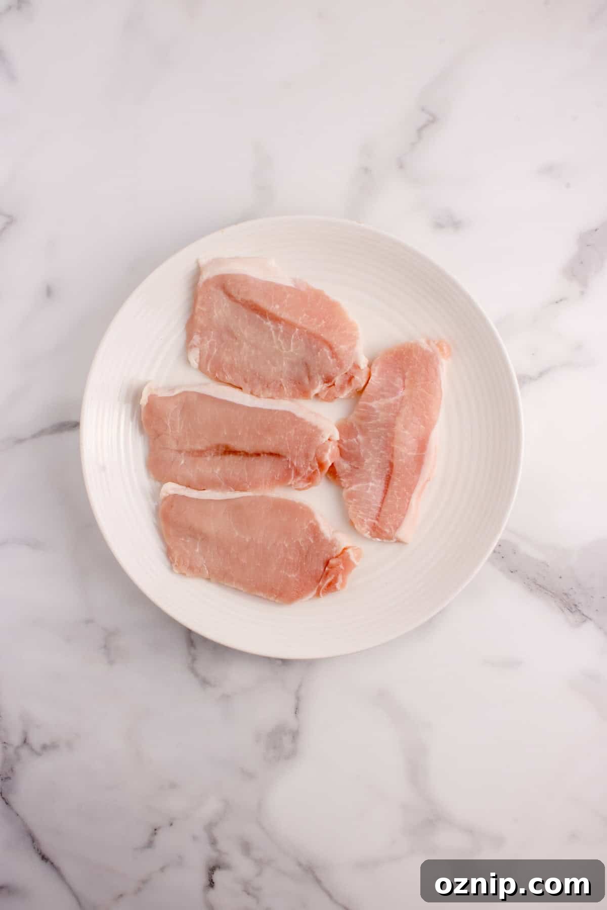 Pork chops patted dry with a paper towel on a plate.
