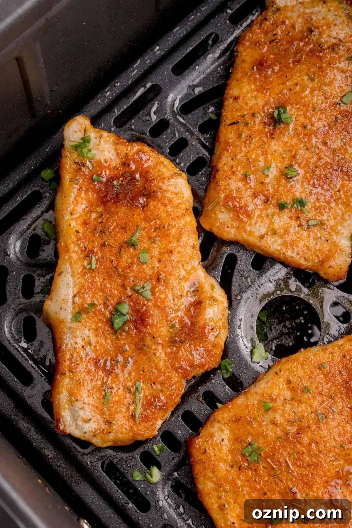 Cooked pork chop in the air fryer, sprinkled with fresh parsley.