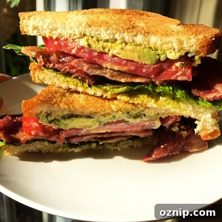 Stacked BLT sandwich with avocado and pesto mayo.