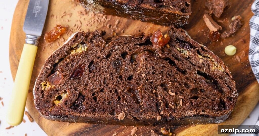 A slice of chocolate cherry sourdough bread laid out horizontally on a round wooden board.