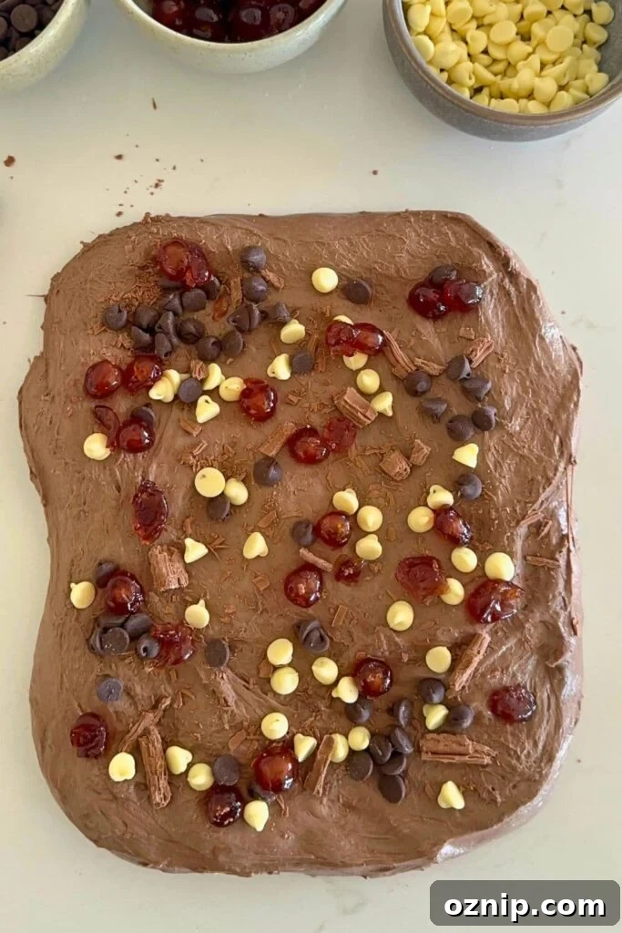 A rectangle of chocolate sourdough decorated with white and semi sweet chocolate chips and glace cherries.