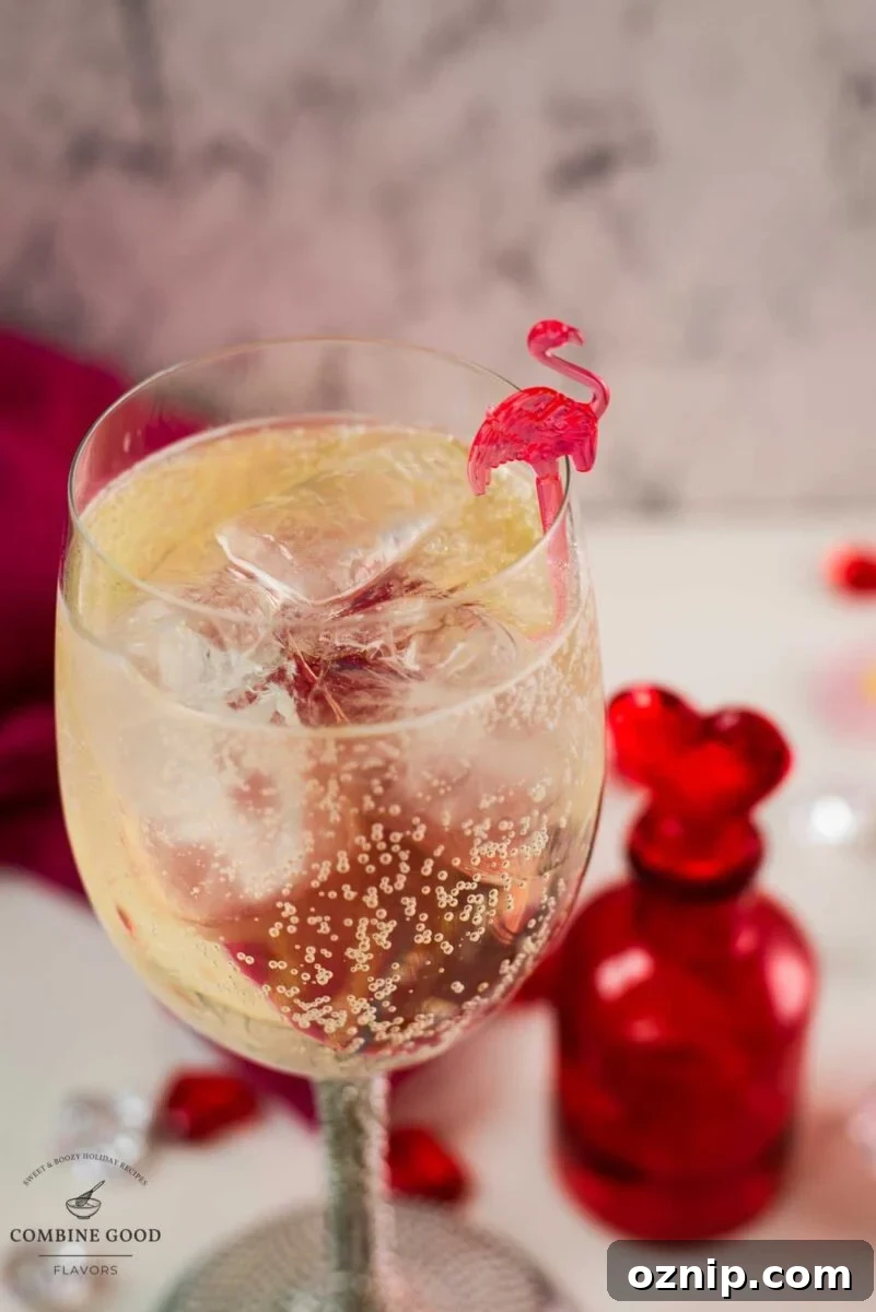 Valentine's Gin Cocktail Recipe for a Romantic Evening 8 Valentines gin cocktail, garnished with a gorgeous flamingo cocktail pick, served in wine glass. Placed on a mirrored coaster next to a heart shaped flask.