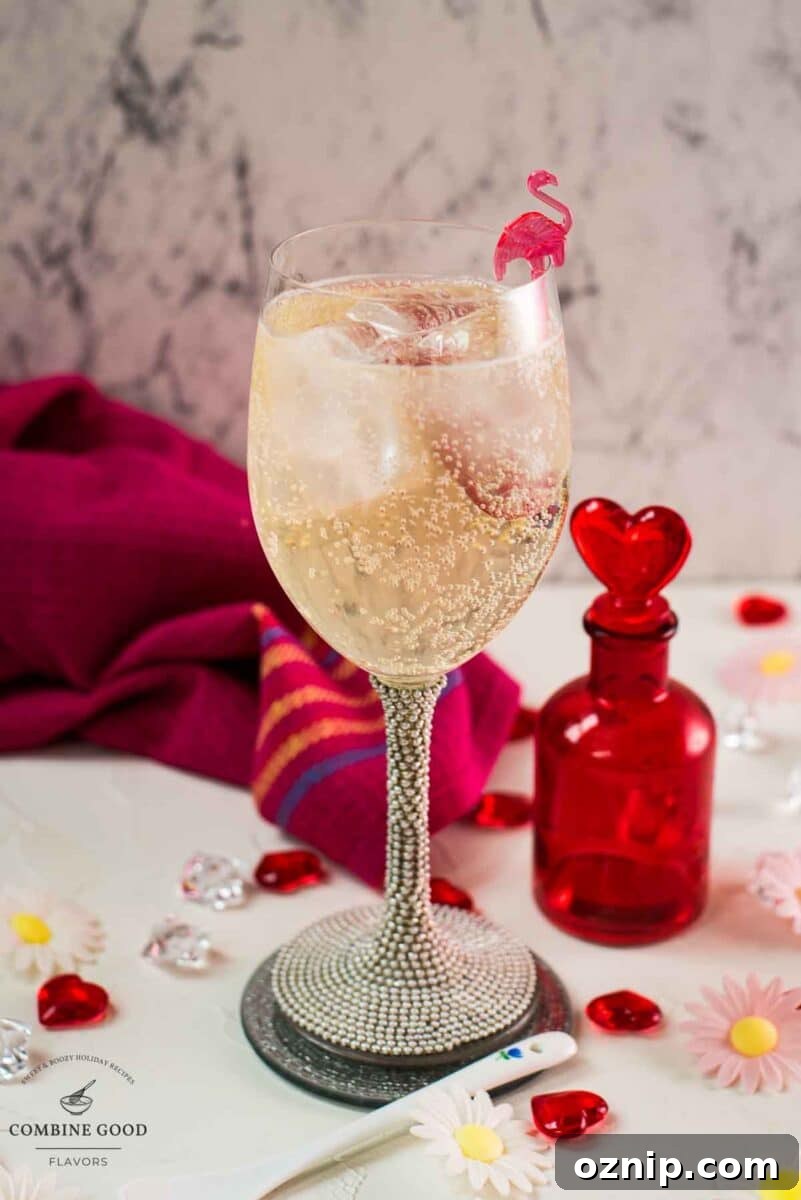 Valentine's Gin Cocktail Recipe for a Romantic Evening 9 Valentines gin cocktail, garnished with a gorgeous flamingo cocktail pick, served in wine glass. Placed on a mirrored coaster next to a heart shaped flask.