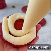 Chewy Red Velvet Cake Mix Cookies Recipe 19 Pipping the frosting onto the underside of the cookie.