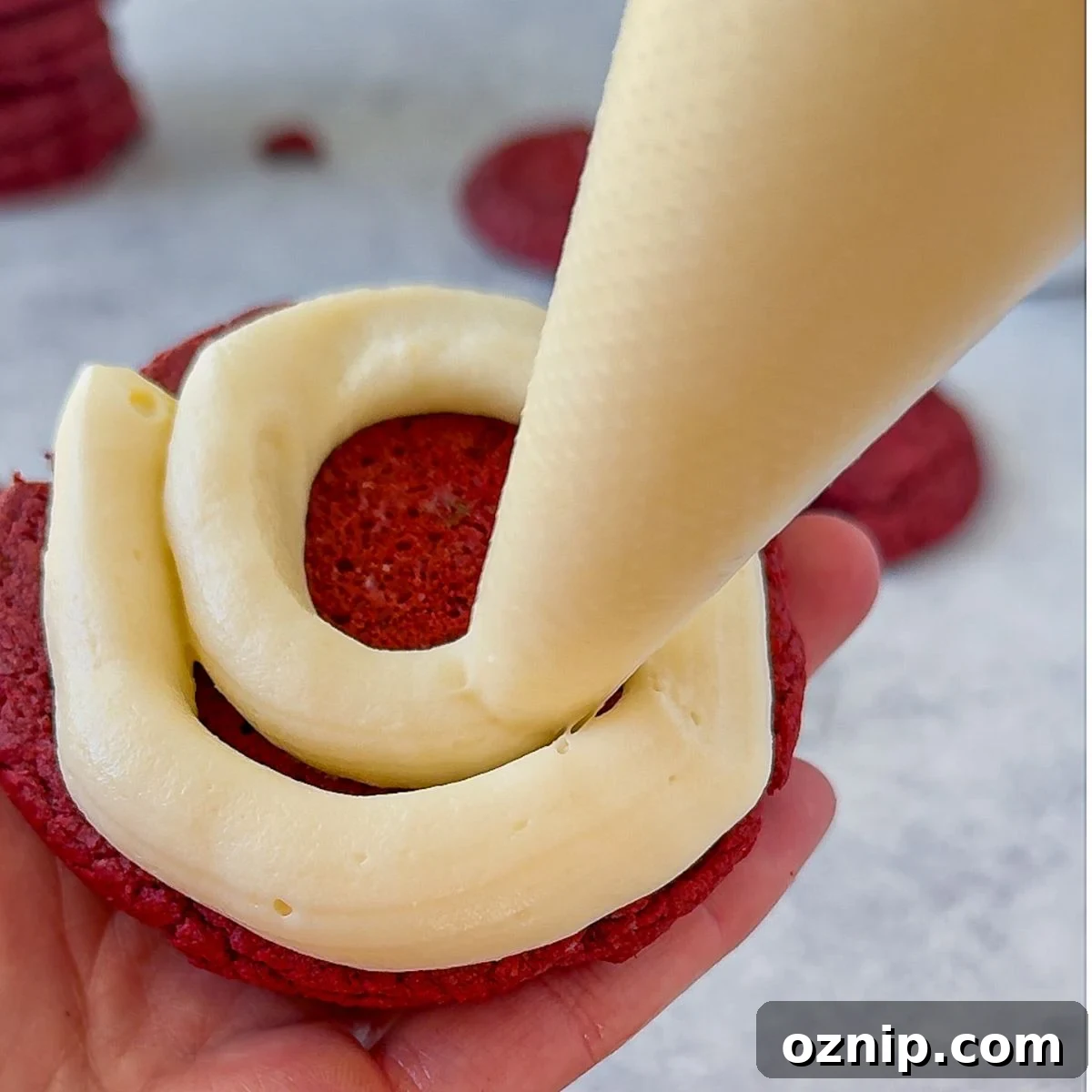 Chewy Red Velvet Cake Mix Cookies Recipe 7 Pipping the frosting onto the underside of the cookie.