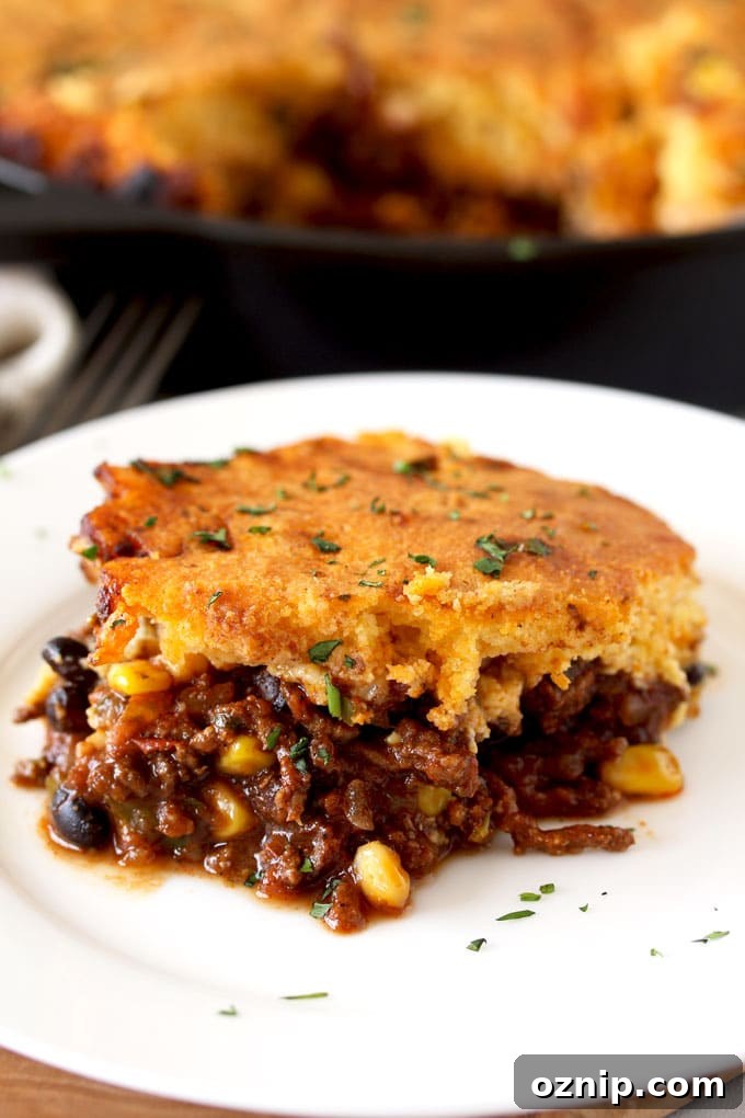 Close up view of a piece of cornbread tamale pie on a white plate