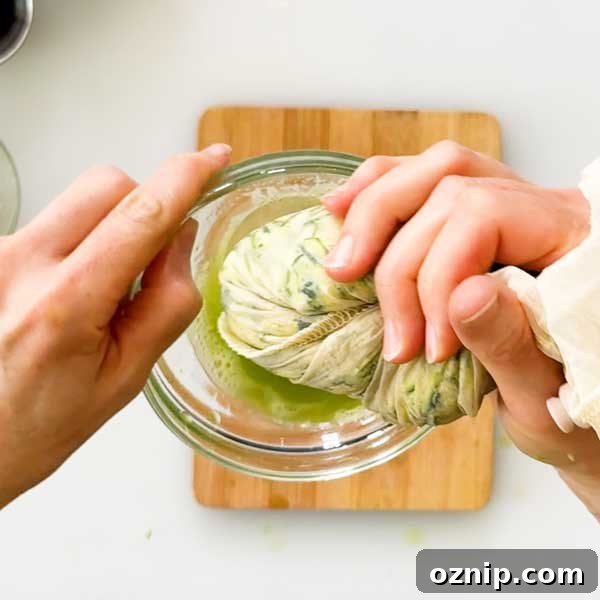 Squeezing the liquid out of the shredded zucchini in a strainer bag.