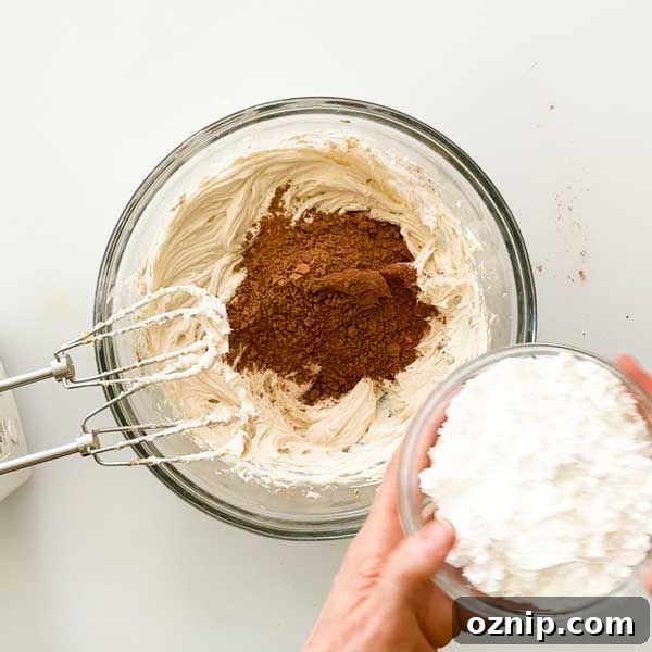 Adding the powdered sugar to the frosting mixture.