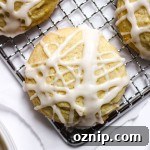 A lemon sugar cookie with lemon glaze on a wire cooling rack.