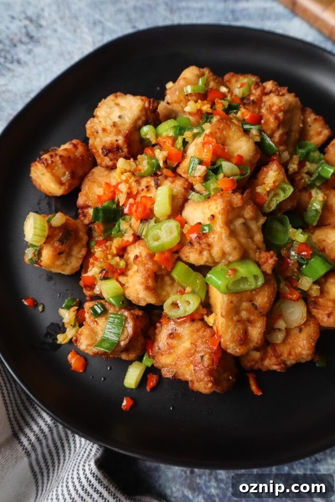 Crispy Salt and Pepper Tofu in the Air Fryer 3 black plate with salt and pepper tofu topped with green onion, red chili pepper, and garlic