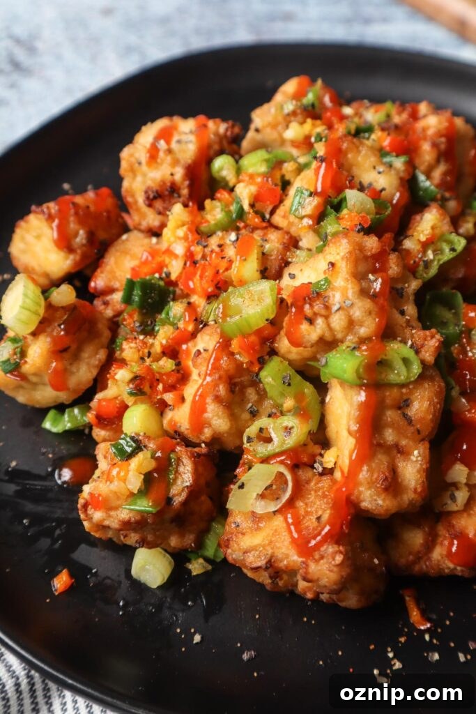 Crispy Salt and Pepper Tofu in the Air Fryer 4 black plate with salt and pepper tofu topped with green onion, red chili pepper, and garlic