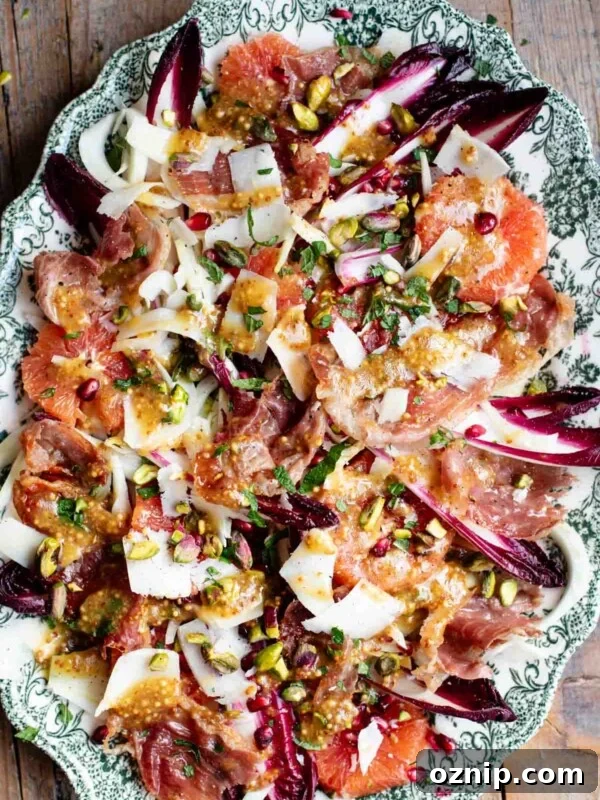 A green serving platter with a festive, colourful salad filled with blood orange, raddichio, fennel, pomegranate, pistachios and prosciutto.