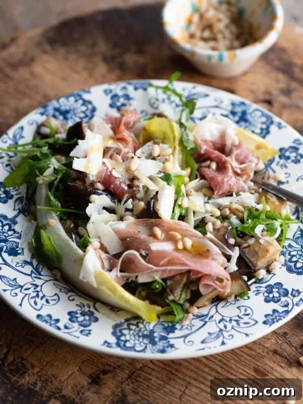 A close up of an eggplant and farro salad on a blue patterned plate on a wooden table.