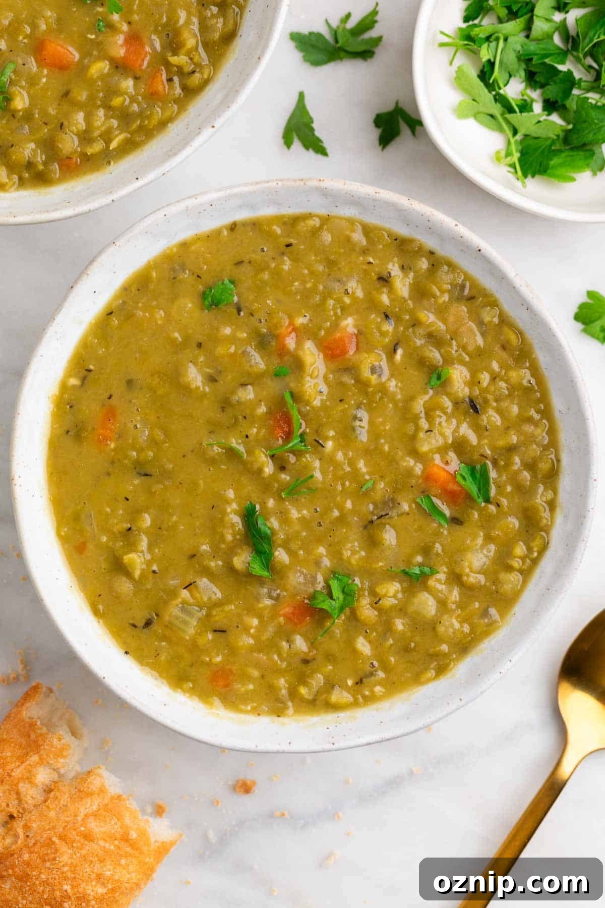 Hearty Vegan Split Pea Soup Recipe 8 Vegan split pea soup with bread, parsley, and a spoon.