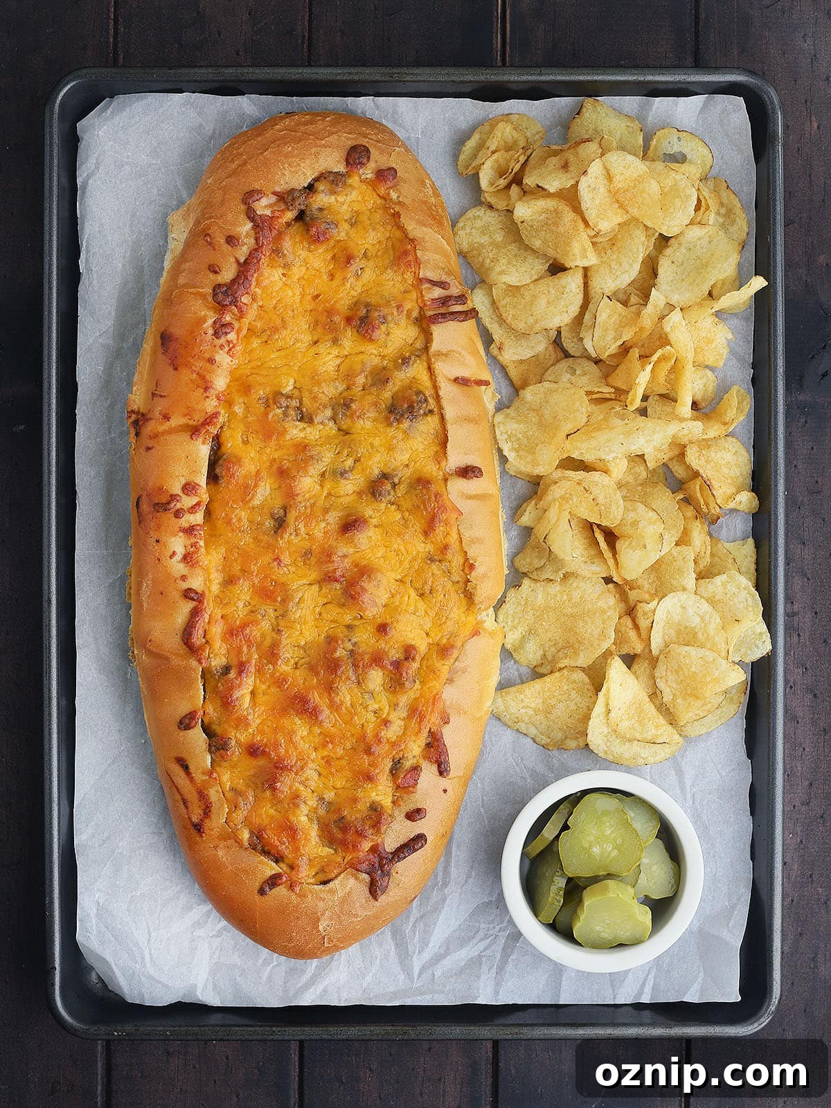 Bacon Cheeseburger Stuffed French Bread Recipe 14 baked bacon cheeseburger stuffed French bread on a parchment paper lined baking sheet