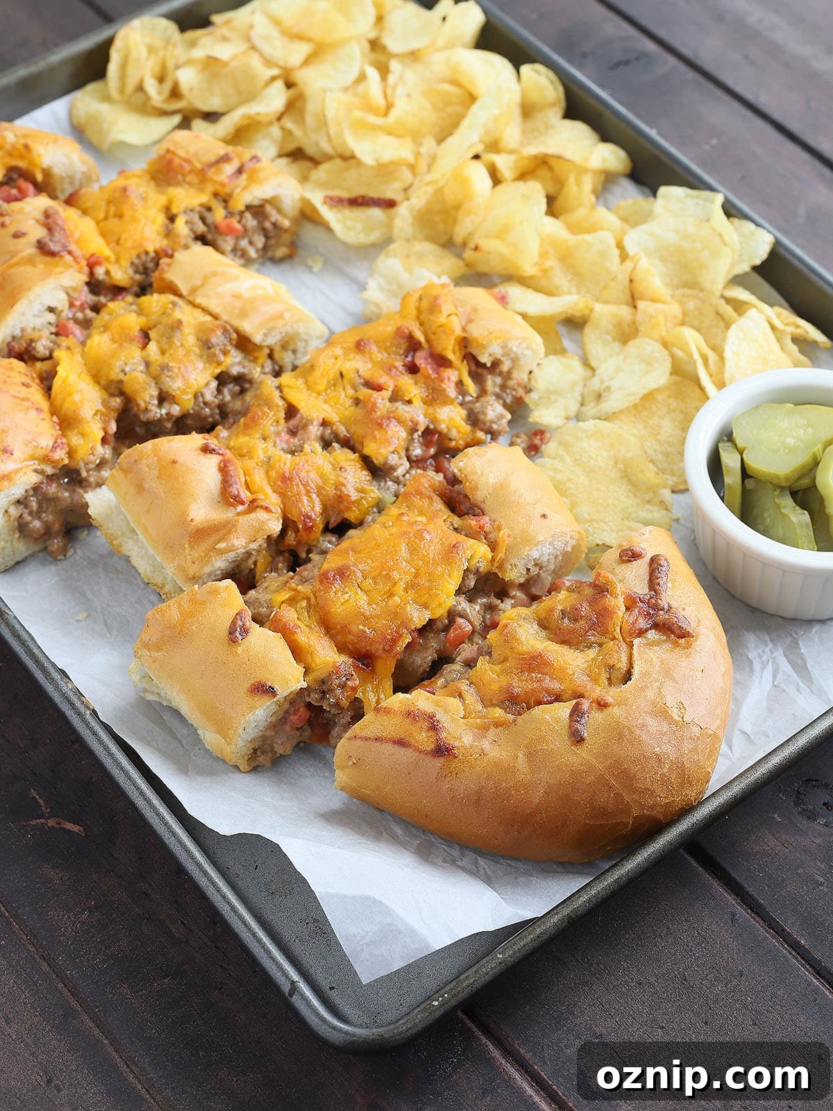 Bacon Cheeseburger Stuffed French Bread Recipe 15 sliced bacon cheeseburger stuffed French bread on a parchment paper lined baking sheet
