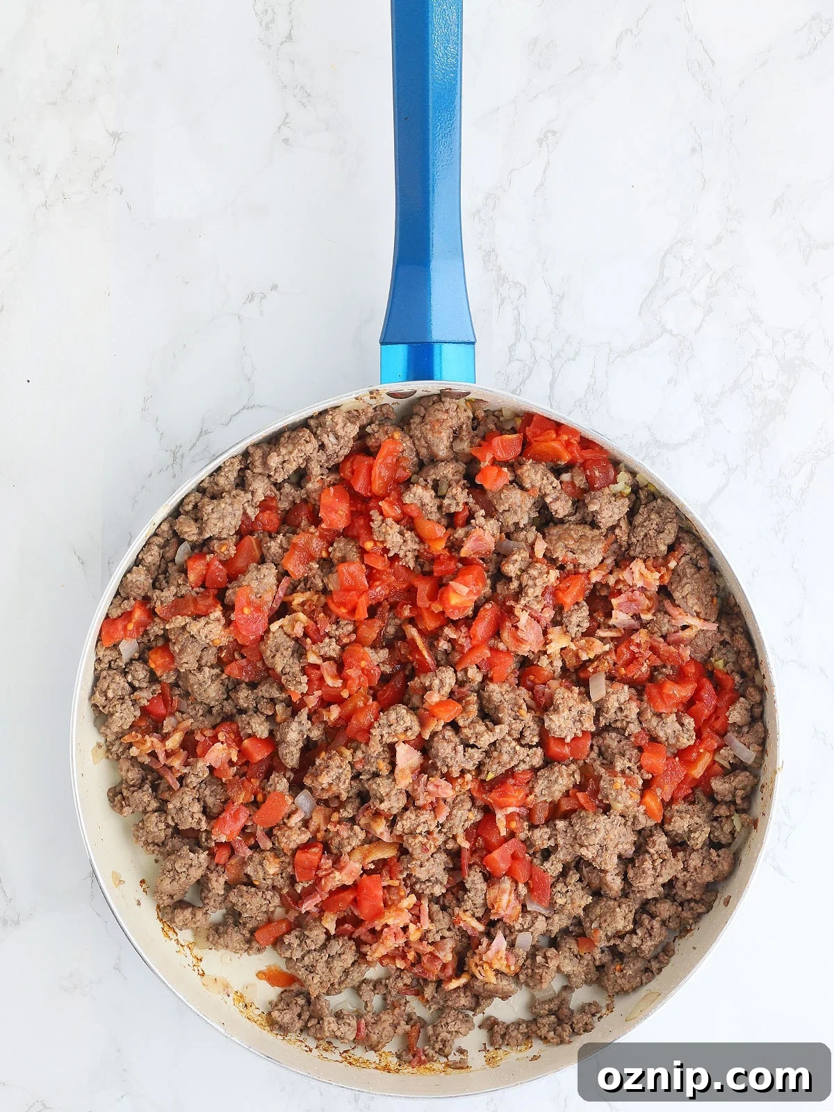 Bacon Cheeseburger Stuffed French Bread Recipe 5 browned ground beef, tomatoes, dill pickles, bacon and garlic mixed together in a blue skillet