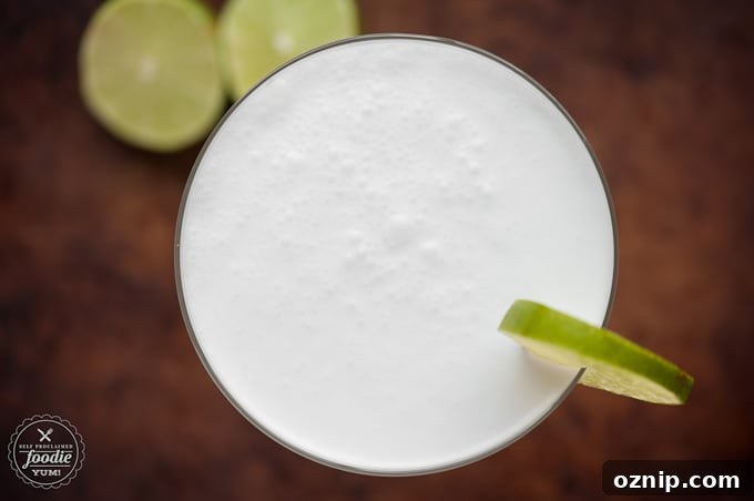 Top of a homemade coconut lime blended daiquiri garnished with lime slices