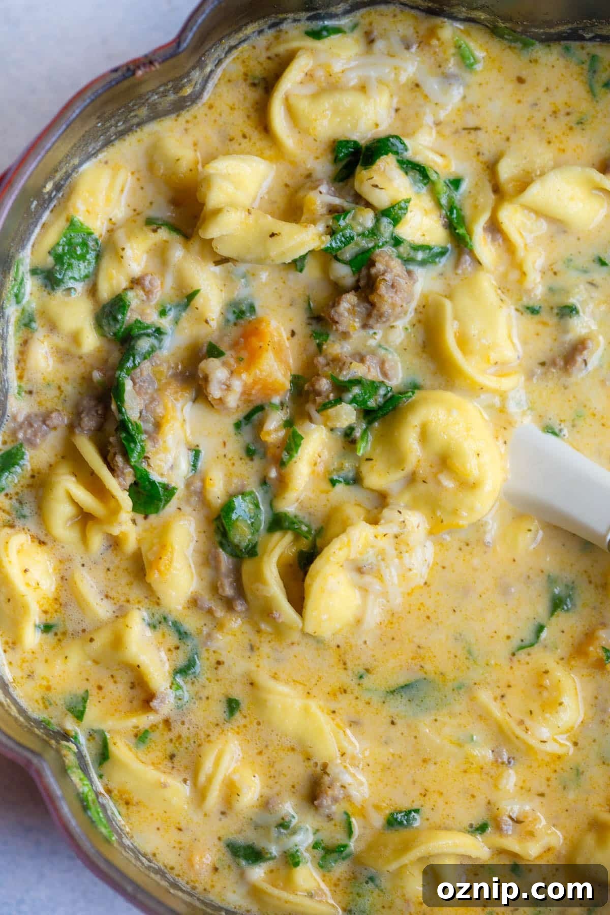 Creamy Butternut Squash and Sausage Tortellini Soup in a large soup pot shaped like a pumpkin.