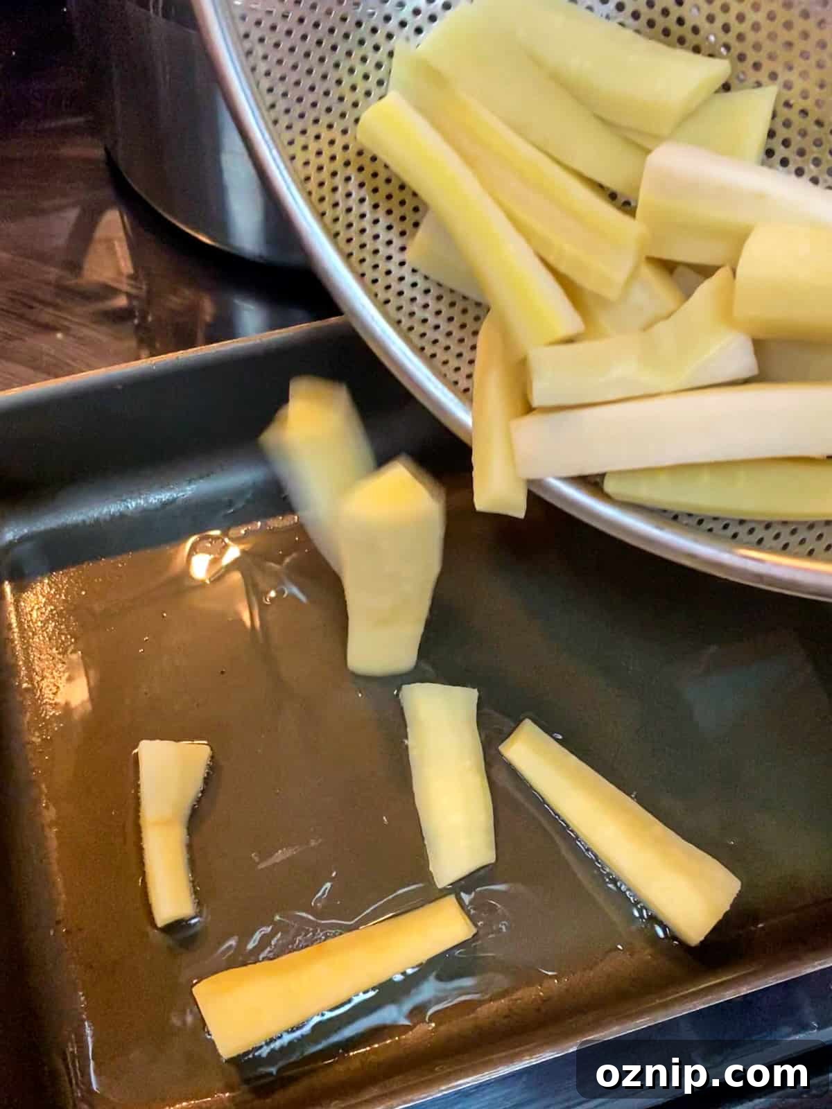Photo of drained parsnips going into the pan of hot oil.
