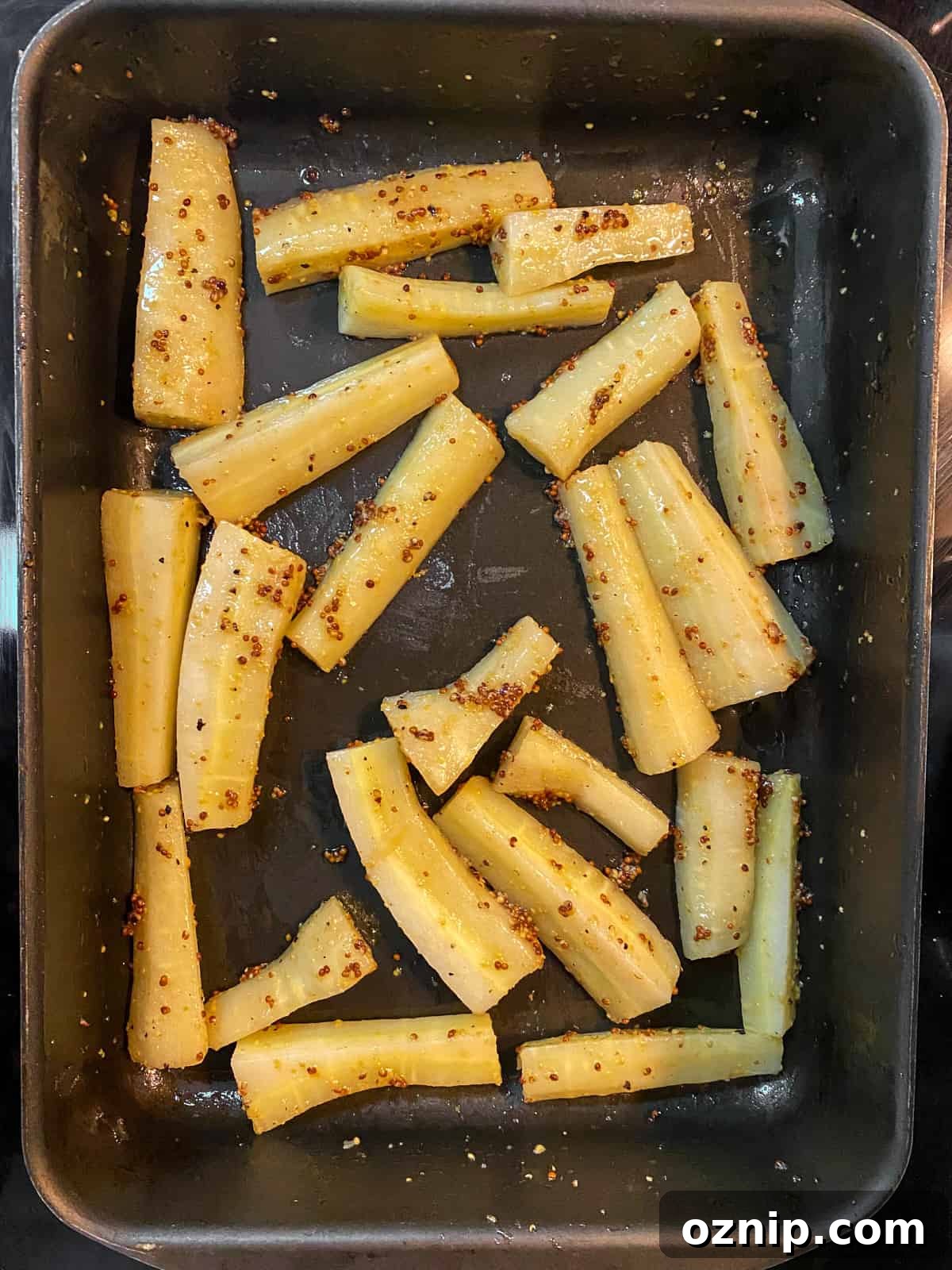 Photo showing the parsnips in a pan mixed with maple syrup and mustard, before cooking.