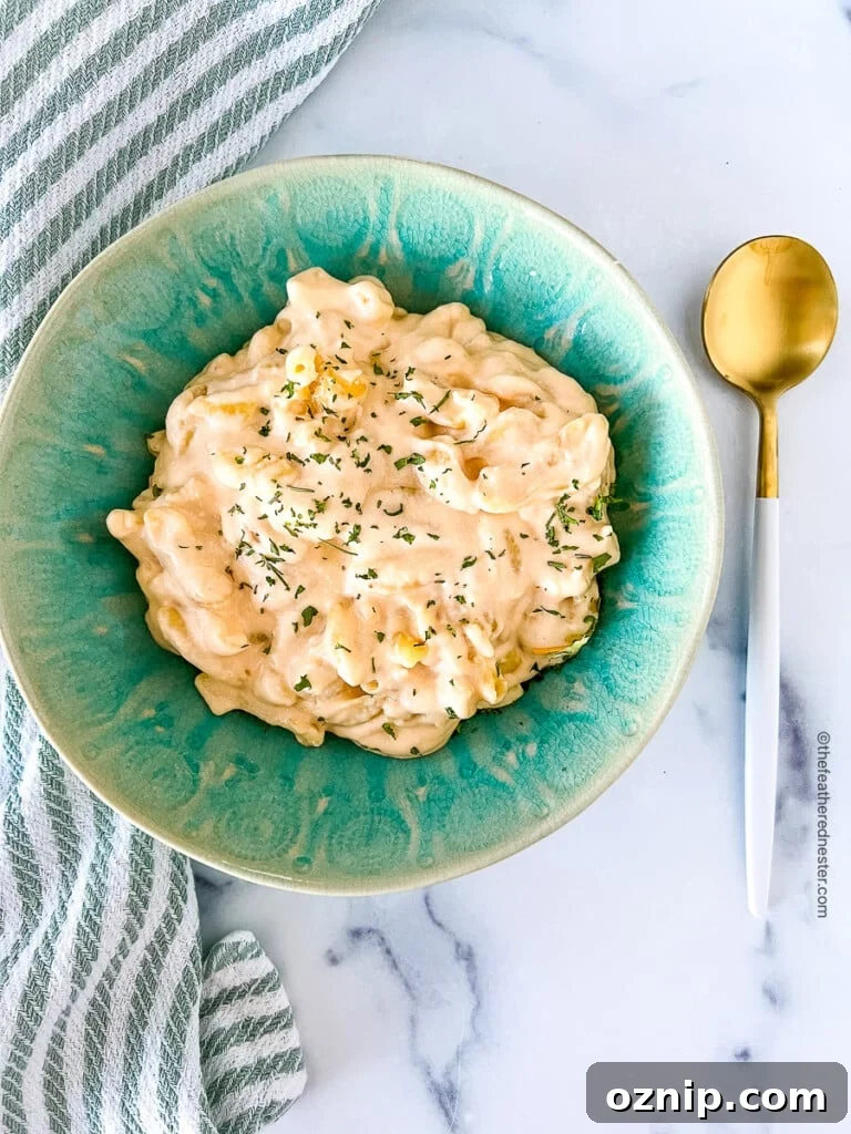 Slow cooker mac and cheese on a green bowl and a spoon at the side.