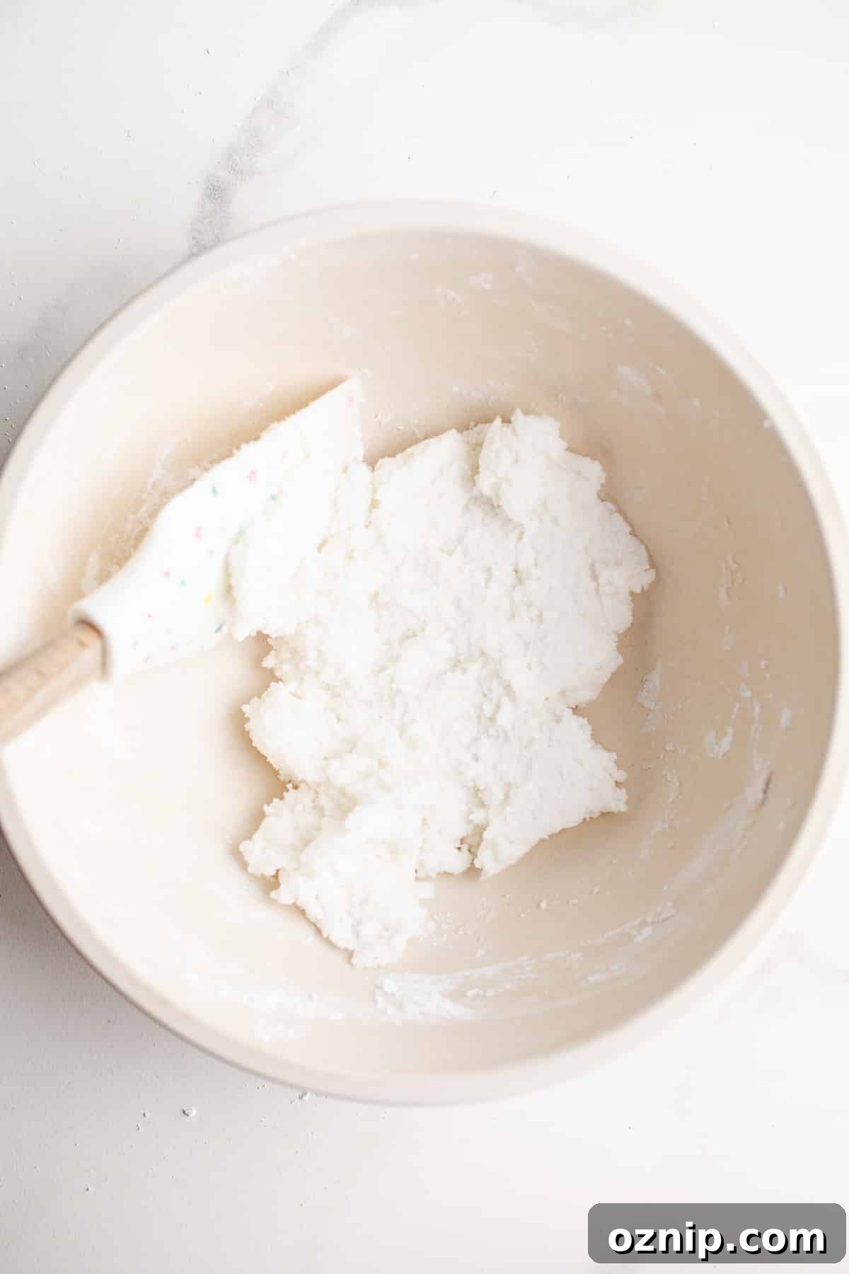 Powdered sugar and coconut oil in a mixing bowl.